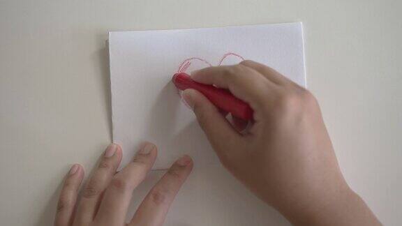 一位妇女用蜡笔在白纸上画了一颗红心