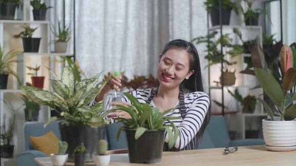 微笑的亚洲妇女在家里浇植物
