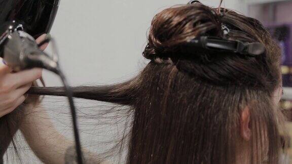 女美发师在美发厅用吹风机给顾客吹干头发