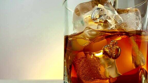特写的酒保倒威士忌在饮用玻璃与冰块在温暖的白色背景时间放松喝威士忌