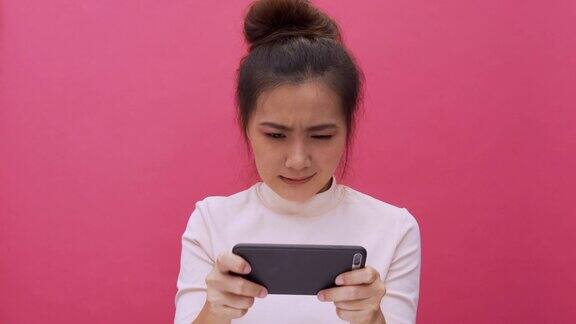 女人玩游戏与智能手机上孤立的粉红色4k背景