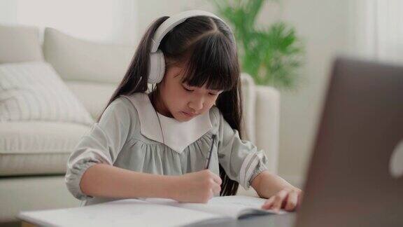 亚洲小女孩戴着耳机在家学习