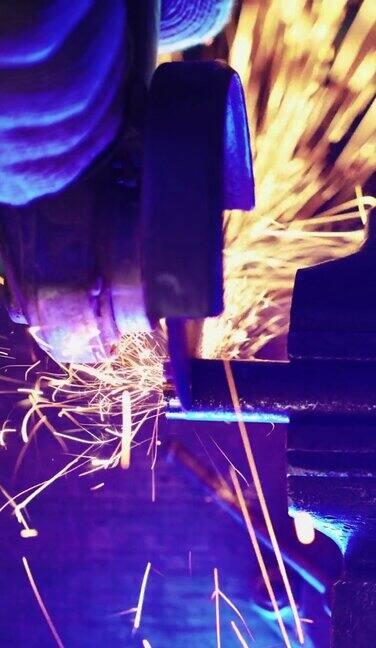垂直视频专业工人作品生产与金属使用圆锯火花从切割金属的地方飞钢铁工业和车间概念旋转的金刚石刀片蓝色的灯光