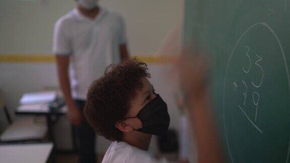 学生戴着口罩在黑板上做数学题