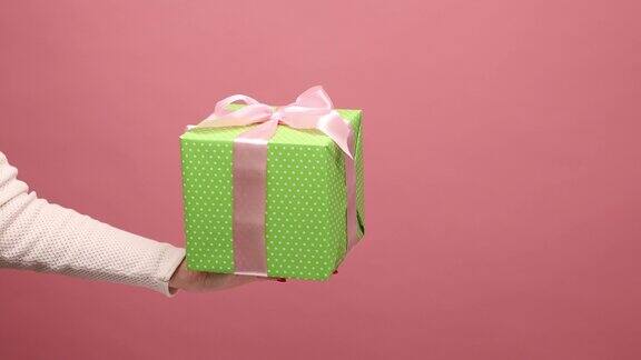 女人手拿着带丝带的绿色礼盒在节日赠送礼物