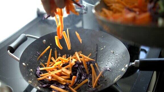 在厨房炉子上的热锅里加入胡萝卜片食物准备以800帧秒的超级慢动作落下