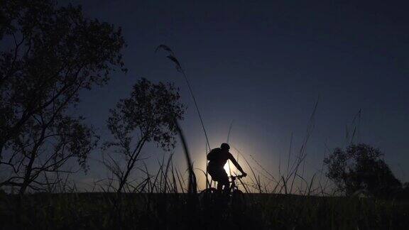 一个年轻人在日落时分积极地骑着自行车