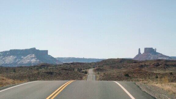 移动镜头从一辆汽车的角度拍摄的道路而行驶在一条公路州际公路在亚利桑那州的沙漠在一个明亮的阳光明媚的日子与山脉和岩石在远处
