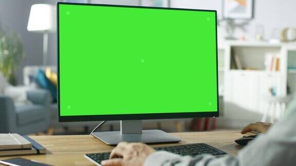 在肩上的职业自由职业者工作的绿色模型屏幕个人电脑从家里男人的手在打字他在他舒适的客厅里用电脑浏览互联网