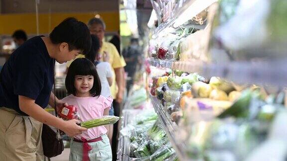 一个亚洲华人家庭周末在超市的冷藏区购买蔬菜
