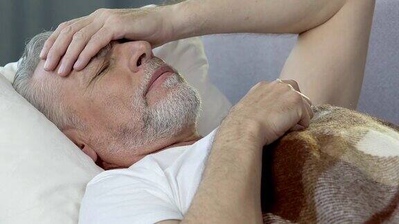 老人躺在床上睡不着手捂着额头头痛得厉害