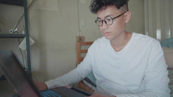 Slomo:年轻的亚洲设计师坐在卧室里用笔记本电脑在家工作