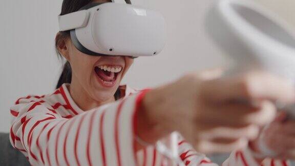 年轻女子佩戴VR头盔体验模拟数字世界拳击姿势在家中客厅玩动作模拟器游戏手机app