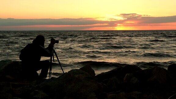 摄影师在日落时拍摄海景照片