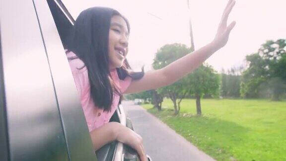 孩子们从车窗探出头来微笑着快乐的亚洲人微笑着看着车外的公路旅行时间女孩在车里玩得很开心