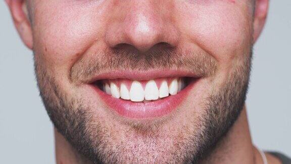 嘴的特写作为一个男人与完美的牙齿微笑在相机在工作室