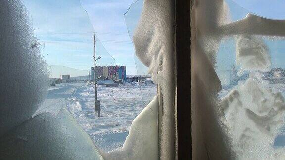 在废弃的城市里一所废弃的房子的破碎冰冻的窗户里飘着雪花