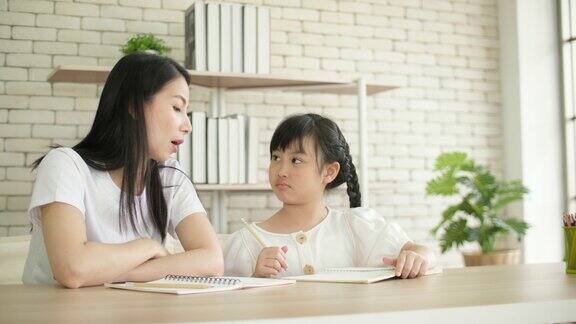 年轻的母亲为她的孩子讲解家庭作业在家学习