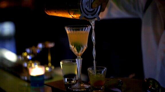 调酒师在酒吧用酒杯混合鸡尾酒靠近侍者的手将酒精饮料倒入玻璃杯