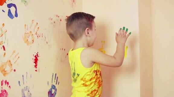 快乐可爱的小男孩在墙上留下五颜六色的手印玩得很开心年轻的幸福的家庭母亲和孩子Slowmotion