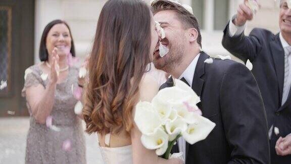 新婚夫妇亲吻客人们向他们扔花瓣