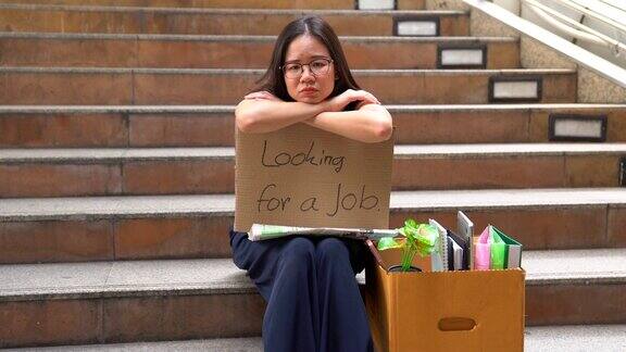 被解雇的办公室职员乞求工作的女人坐在街上乞求帮助的无家可归者经济危机经济改革观念一个白领被解雇了她坐在人行道上乞求一份新工作
