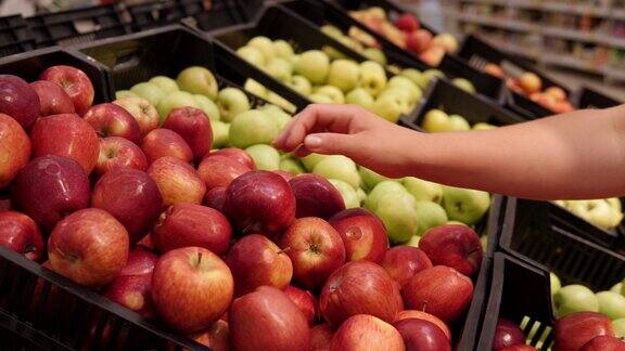 一个女人在超市挑选红苹果的特写