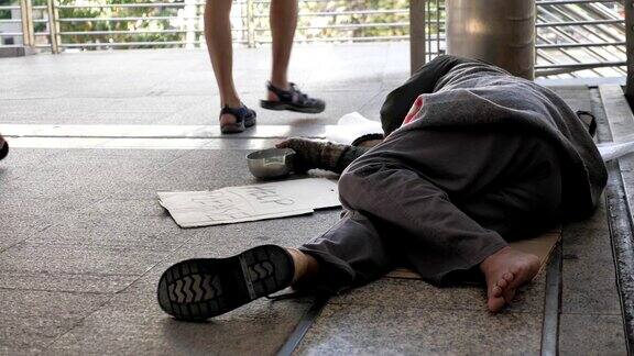 一个穿着脏衣服睡在街上寻求帮助的无家可归的老人
