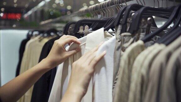 在服装店的衣架上挑选衣服的女人