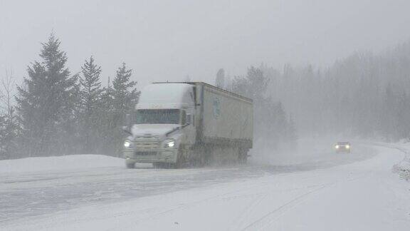 在凛冽的暴风雪中汽车和卡车在乡间小路上小心翼翼地行驶