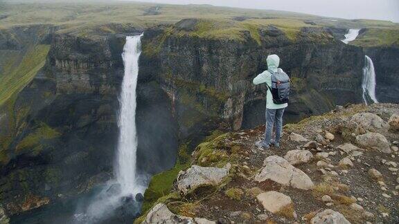 在冰岛高地上一名女子背着背包欣赏海弗斯瀑布