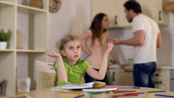 伤心的小女孩坐在餐桌旁愤怒的父母争吵家庭问题