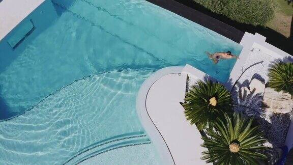 无人机拍摄的男子在游泳池里快速游泳和自由泳