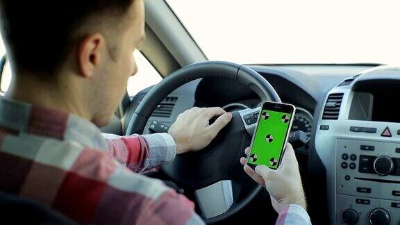 男人坐在现代的汽车里用智能手机工作-绿色屏幕色度键-特写绿色的屏幕色度键