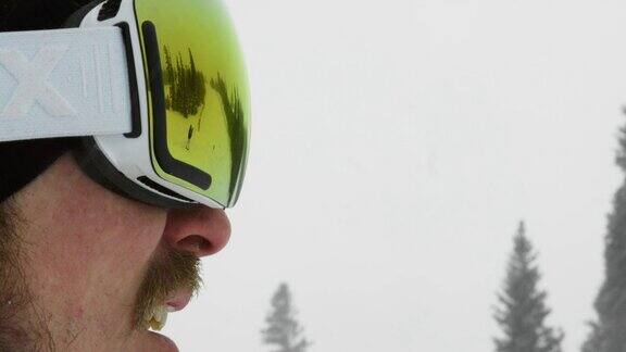 慢动作拍摄三十多岁男性滑雪板运动员微笑戴上他的护目镜准备在一个阴天的冬天滑雪板