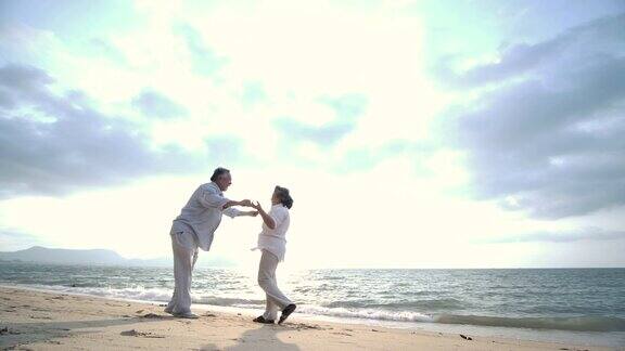 浪漫的亚洲老年夫妇在海滩上跳舞的慢动作