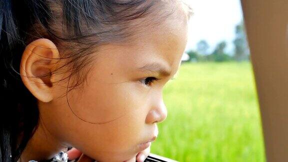 悲伤可爱的亚洲小女孩看着窗外的乡村慢镜头