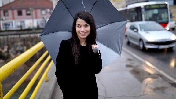 年轻女子撑着伞走在桥上