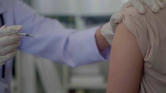 近距离的手亚洲女医生注射在亚洲女孩的手臂
