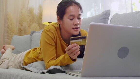 女人拿着信用卡用手提电脑在家工作的女性网上购物电子商务网上银行花钱在家工作网上科技购物概念