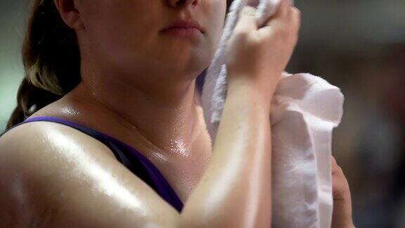 女人用毛巾擦汗在健身房运动累了减肥