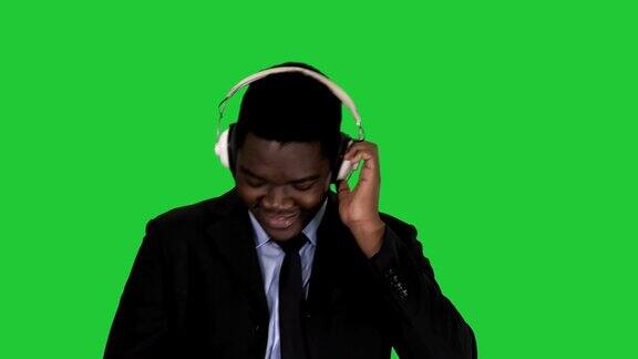 黑人商人戴着耳机在绿色屏幕上随着音乐跳舞
