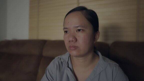 一个亚洲女人晚上在客厅看电视盯着自己的脸