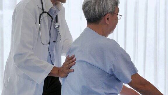 男性物理治疗师工作在背部的年长男性病人与伤害在诊所为病人工作的物理治疗师医疗保健:照顾康复理疗
