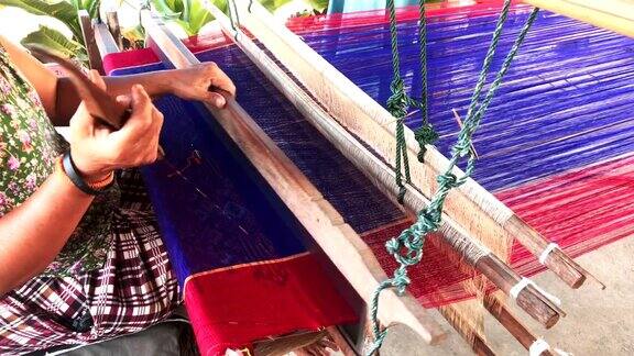 传统的泰国纺织业在手工艺村老妇人在木制织布机上工作纺纱制造棉织物