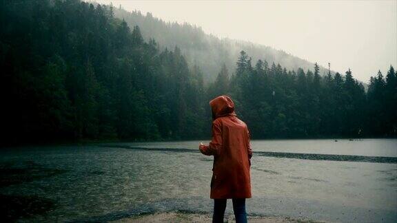 一个穿着雨衣的女人站在倾盆大雨下的湖边