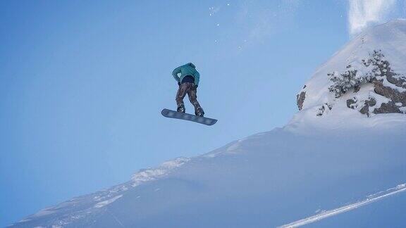 滑雪板从悬崖上跳下来在半空中旋转在刚落下的雪上着陆