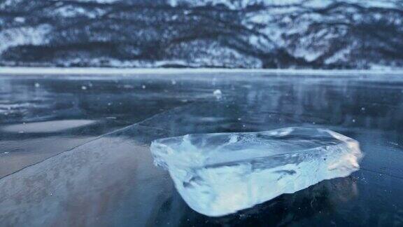 浮冰在冰面上旋转映衬着令人惊叹的山景缓慢的运动镜头移到了冰的后面冰在冰上旋转有神奇的裂缝非常漂亮