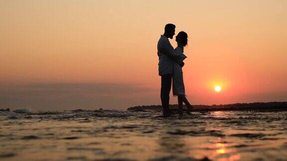 夕阳下沙滩上一对浪漫情侣的剪影