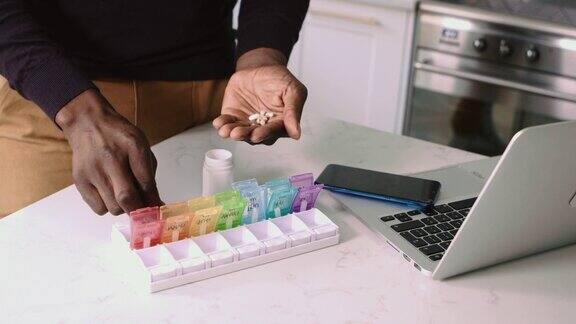 特写的黑人男子的手把处方药放在一个每日药片整理